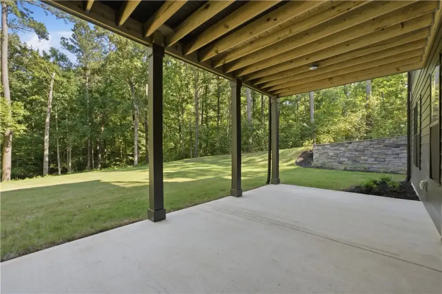 Sheltered concrete patio overlooks a grassy lawn b