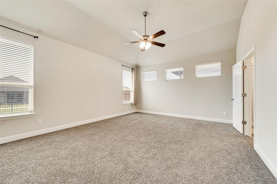 Empty room with lofted ceiling, light colored carpet, and ceiling fan