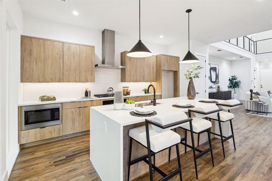 Kitchen featuring a kitchen island with sink, wall chimney range hood, decorative light fixtures, appliances with stainless steel finishes, and dark hardwood / wood-style flooring