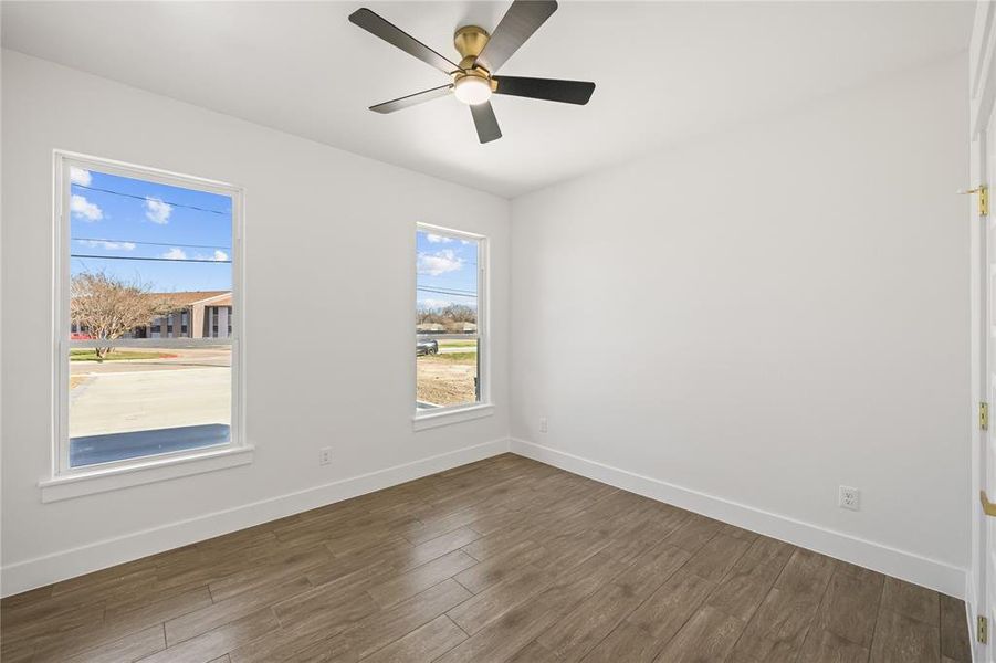 Unfurnished room featuring dark wood-type flooring and ceiling fan