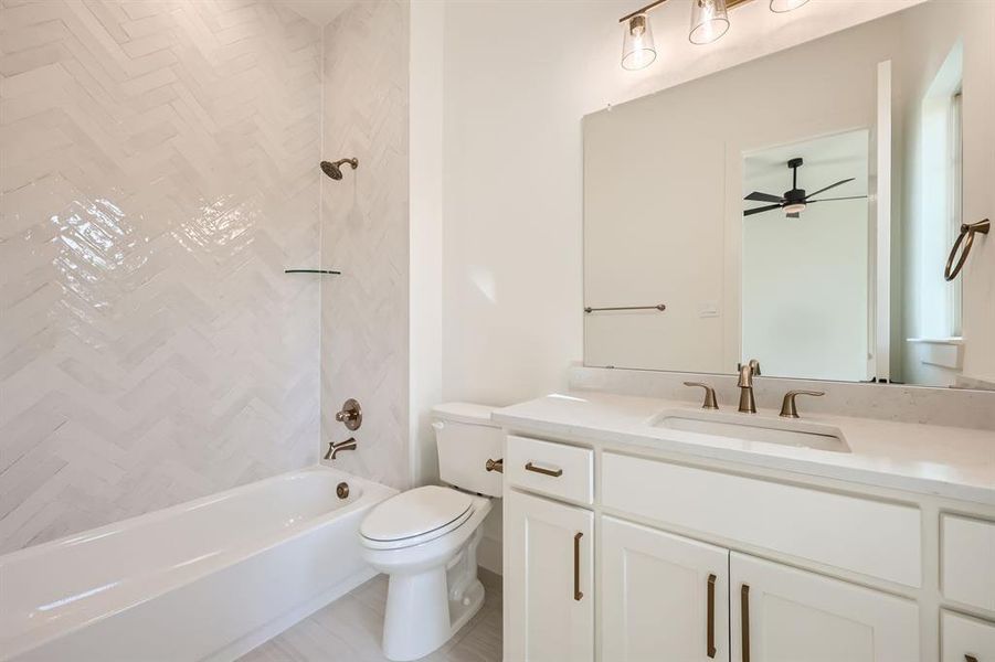 Full bathroom with vanity, toilet, ceiling fan, and tiled shower / bath