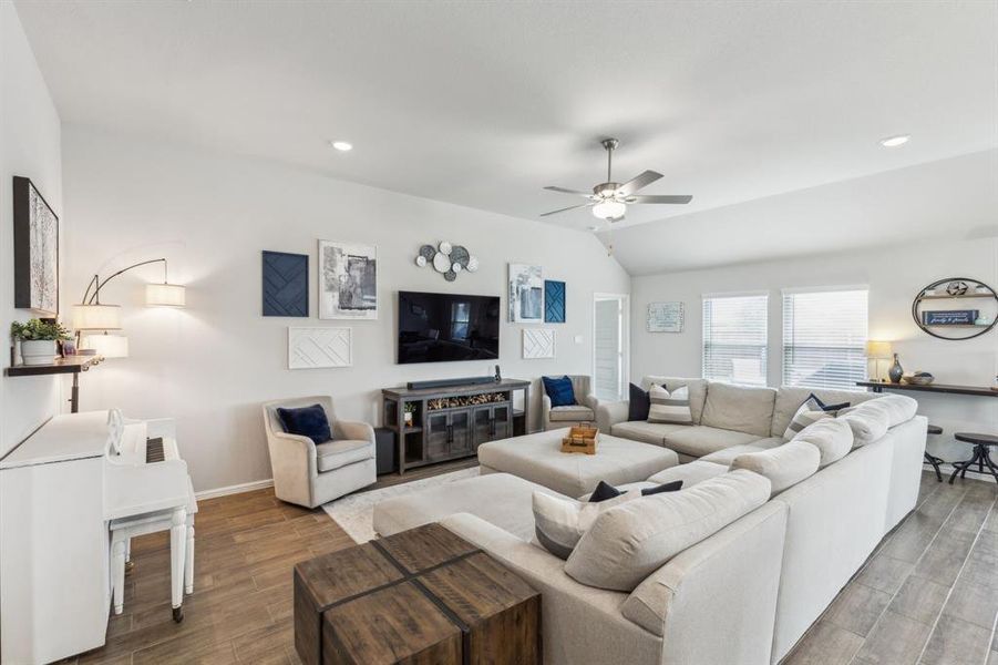 Living room featuring wood look tile floors, baseboards, ceiling fan, recessed lighting, and vaulted ceiling Living room featuring wood look tile floors, baseboards, ceiling fan, recessed lighting, and vaulted ceiling