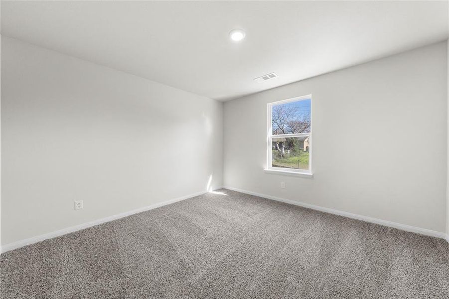 Carpeted spare room featuring visible vents and baseboards