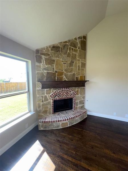 Unfurnished living room with vaulted ceiling, a fireplace, and wood-type flooring