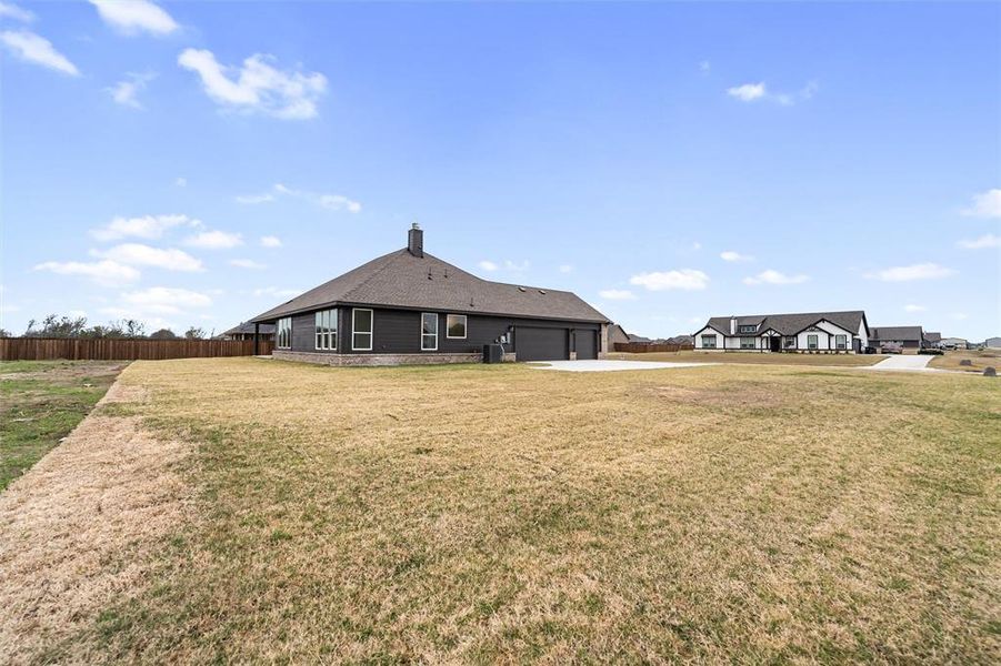 Rear view of property with a chimney, an attached garage, and driveway