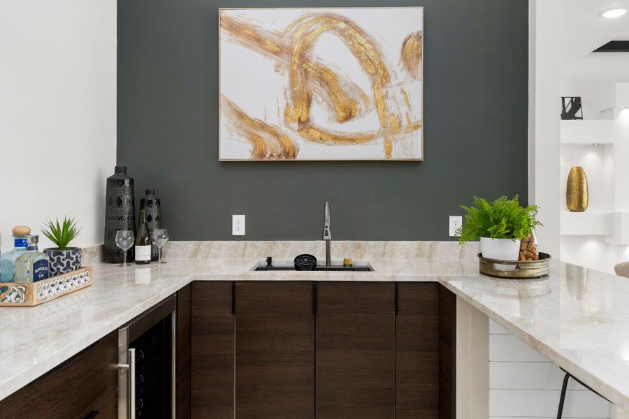 Indoor wet bar with dark wood finish cabinetry, light stone countertops, wine cooler, and modern cabinets