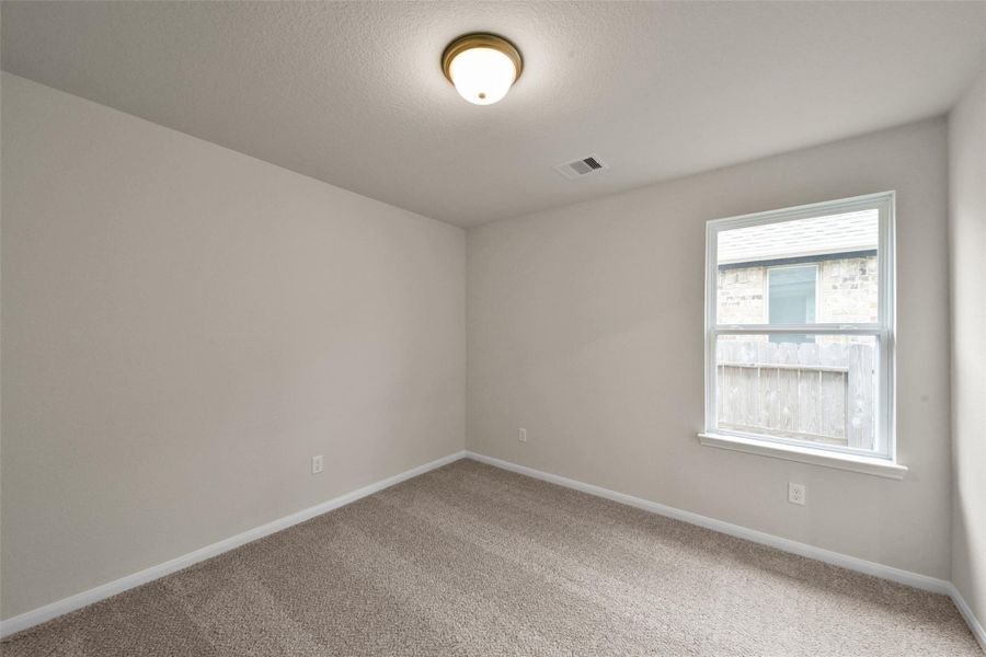 Cozy, sunlit bedroom with plush carpeting and a large window—perfect for relaxation.