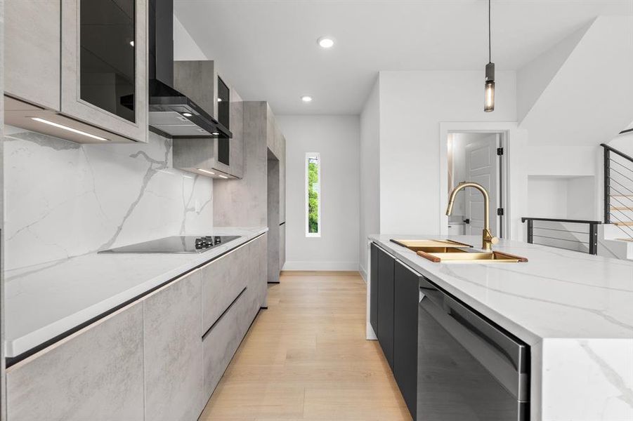 Kitchen featuring dishwasher, wall chimney range hood, a sink, and modern cabinets