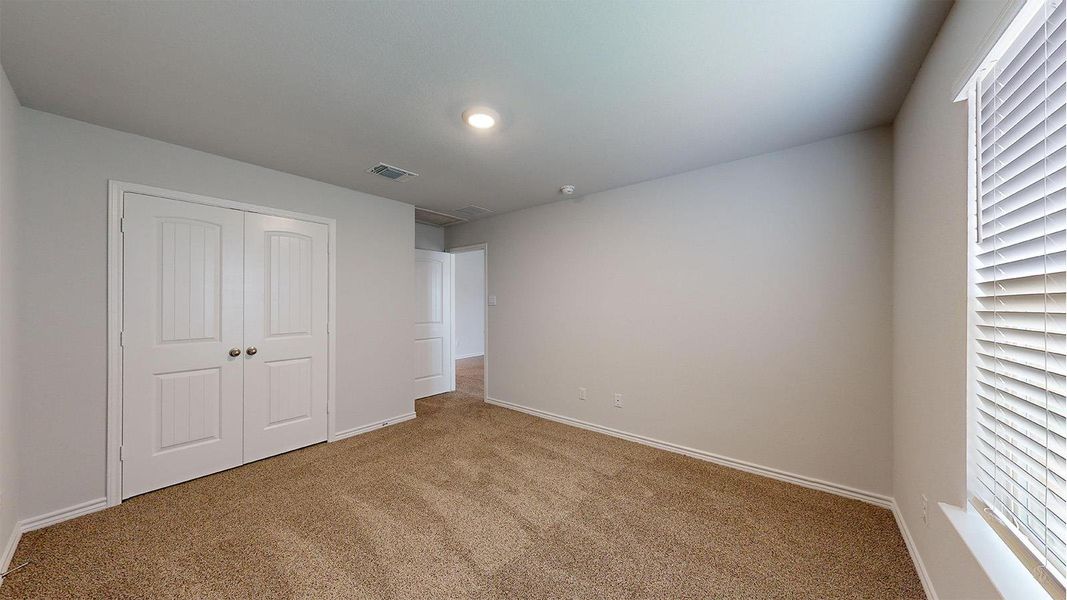 Carpeted room featuring a double-door closet, recessed ceiling lighting, and a window with blinds Carpeted room featuring a double-door closet, recessed ceiling lighting, and a window with blinds