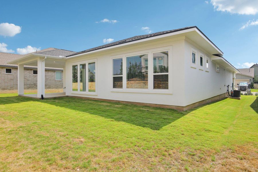 Rear view of property featuring a lawn and a patio