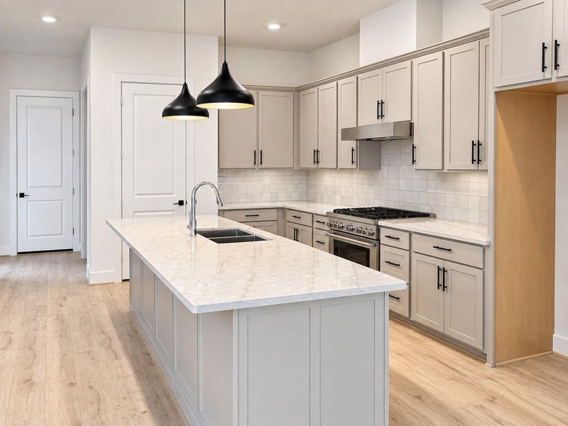 Bright, open kitchen featuring an oversized island, pendant lighting, stainless steel range and vent hood, abundant cabinetry, and sleek black hardware. Bright, open kitchen featuring an oversized island, pendant lighting, stainless steel range and vent hood, abundant cabinetry, and sleek black hardware.