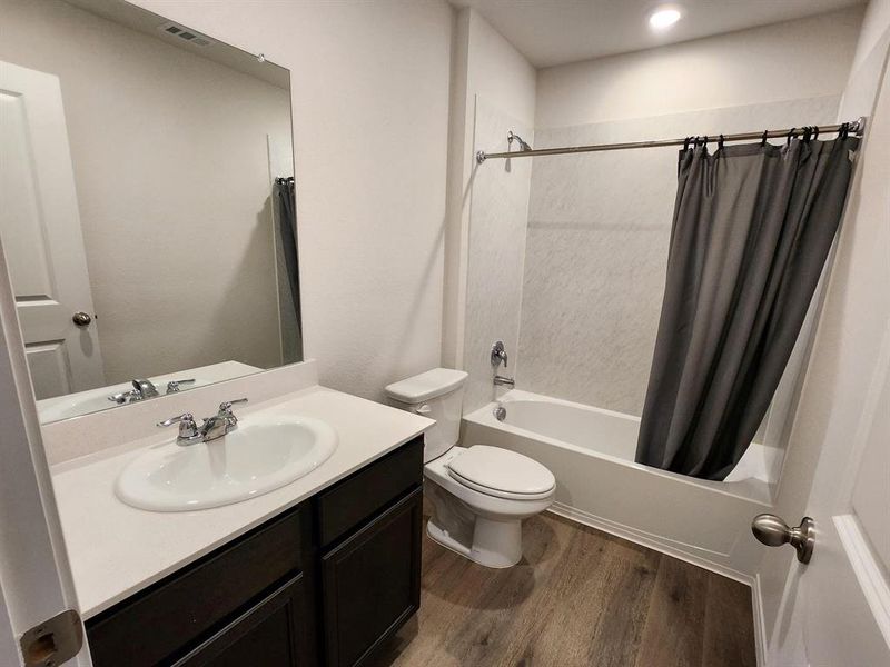 Full bath featuring shower / bath combo with shower curtain, vanity, and dark wood finished floors