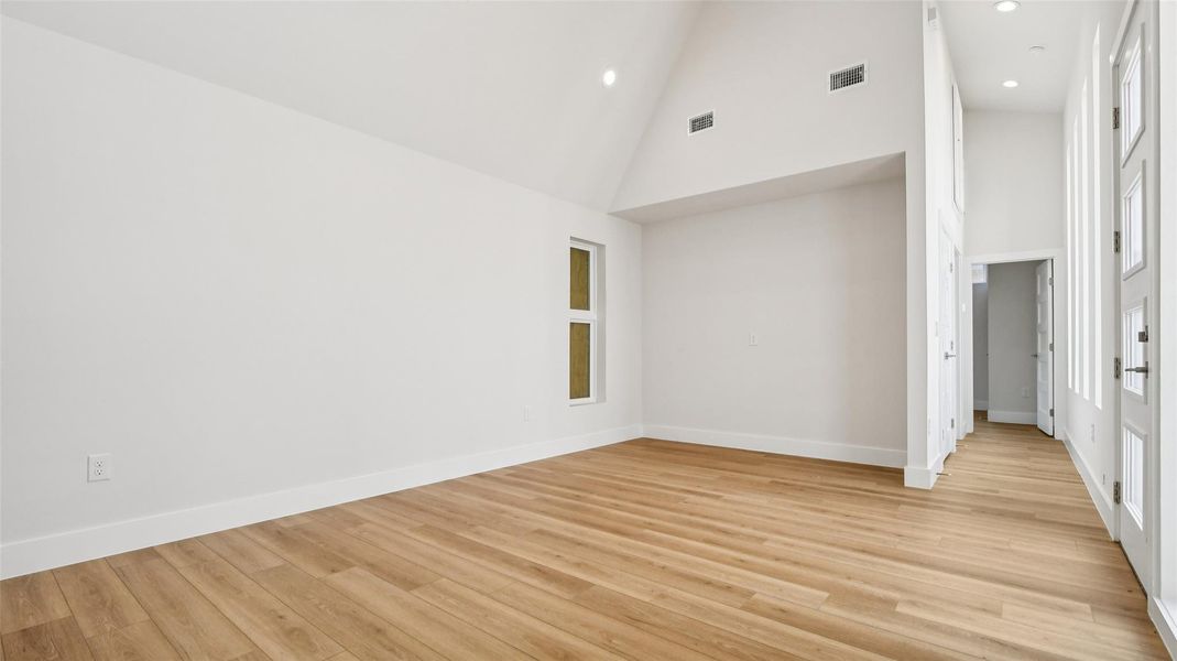 Spare room with high vaulted ceiling, light wood-type flooring, and recessed lighting Spare room with high vaulted ceiling, light wood-type flooring, and recessed lighting