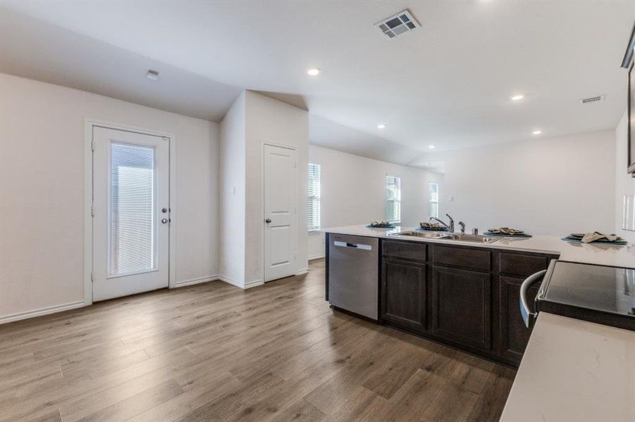 Kitchen featuring light countertops, a peninsula, stainless steel dishwasher, dark brown cabinets, and lofted ceiling Kitchen featuring light countertops, a peninsula, stainless steel dishwasher, dark brown cabinets, and lofted ceiling