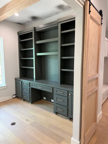 Unfurnished office with light wood-style flooring, a barn door, and built in desk