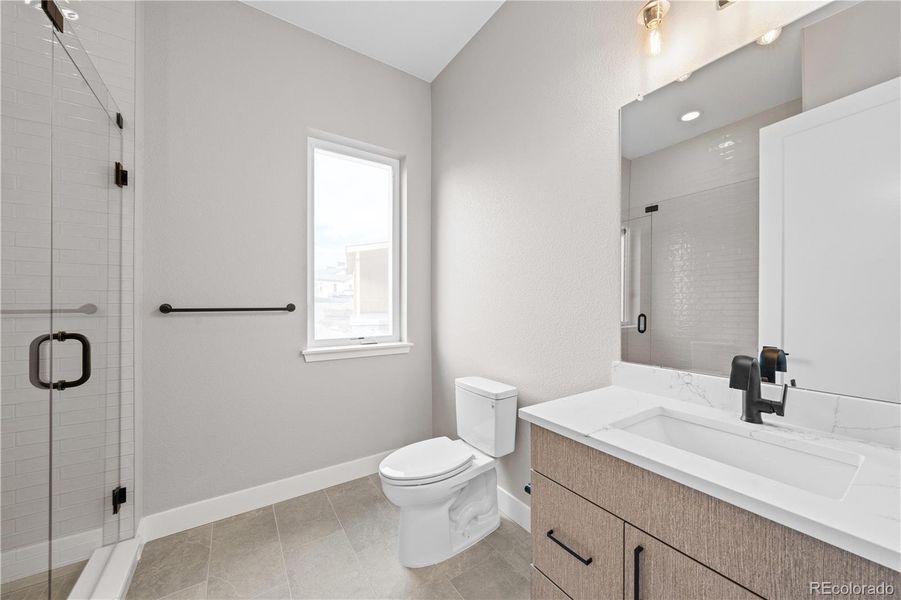 Main level guest bedroom with en suite bathroom and walk-in closet. *This photo has been virtually staged.