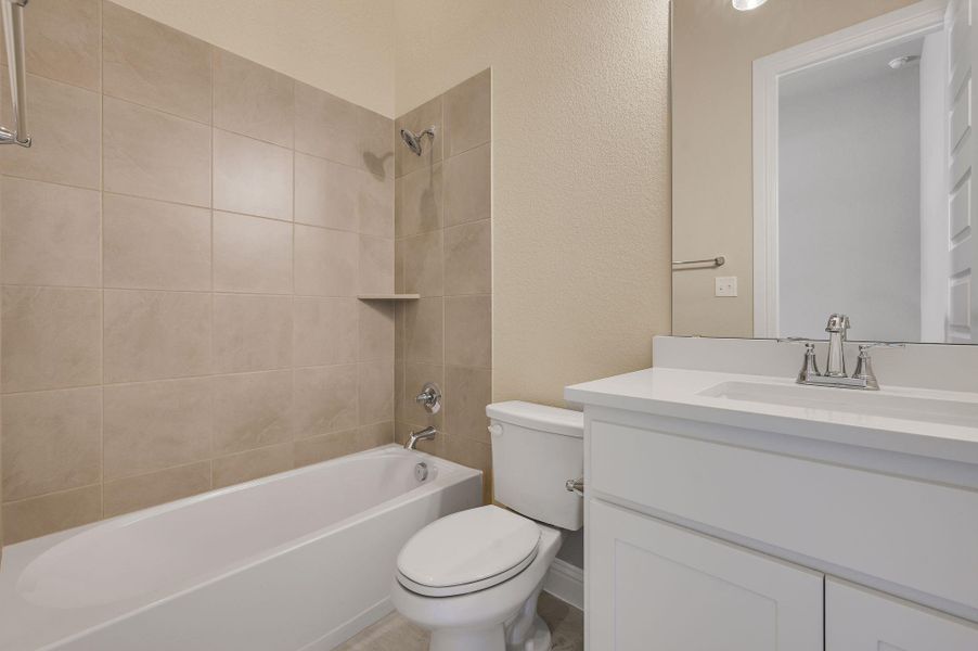 Bathroom with shower / washtub combination, vanity, and a textured wall