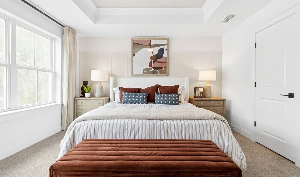 Primary suite with tray ceiling and decorative feature wall Primary suite with tray ceiling and decorative feature wall