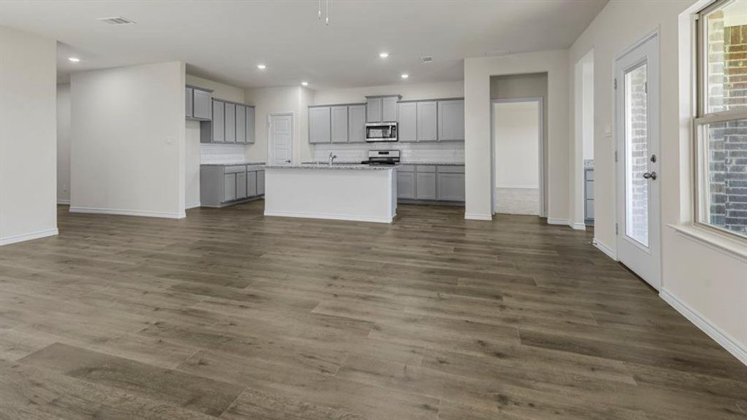 Open-concept living area with wood-look flooring, recessed lighting, and a view of the kitchen