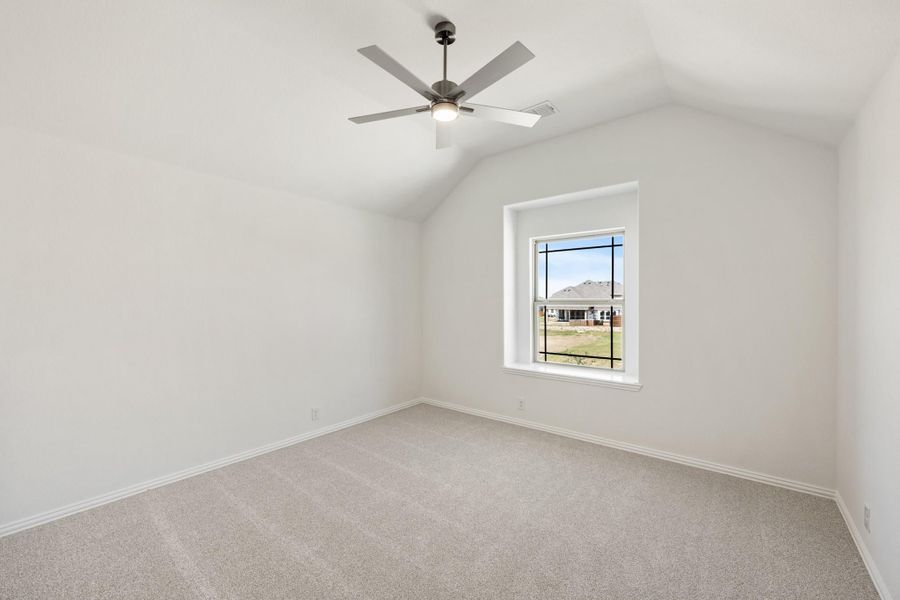 Empty bedroom with vaulted ceiling, ceiling fan, carpet flooring, and single window Empty bedroom with vaulted ceiling, ceiling fan, carpet flooring, and single window