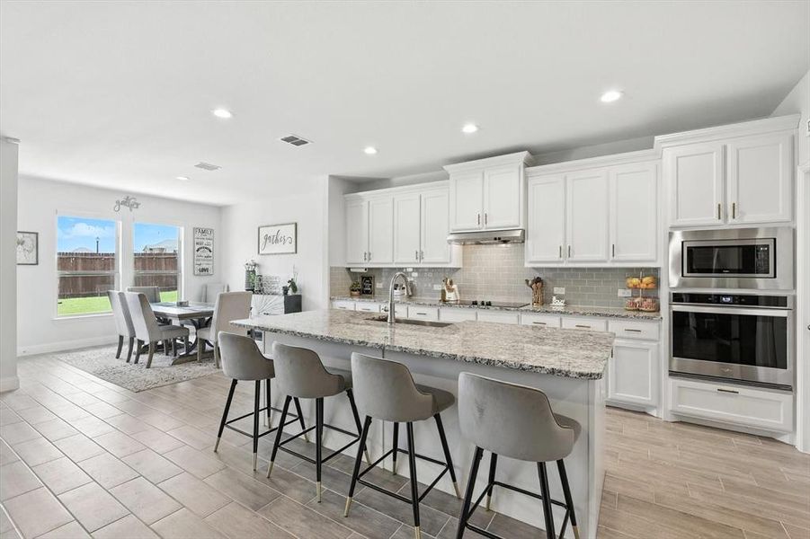 Kitchen with stainless steel appliances, backsplash, recessed lighting, a breakfast bar area, and white cabinets