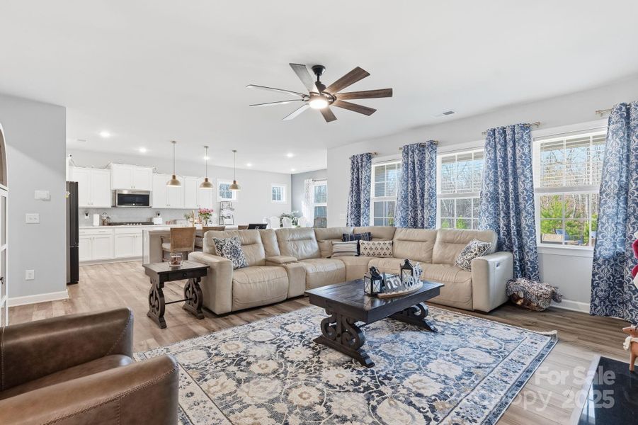 Gather with friends and family in the open living room, flooded with natural sunlight from large picture windows Gather with friends and family in the open living room, flooded with natural sunlight from large picture windows