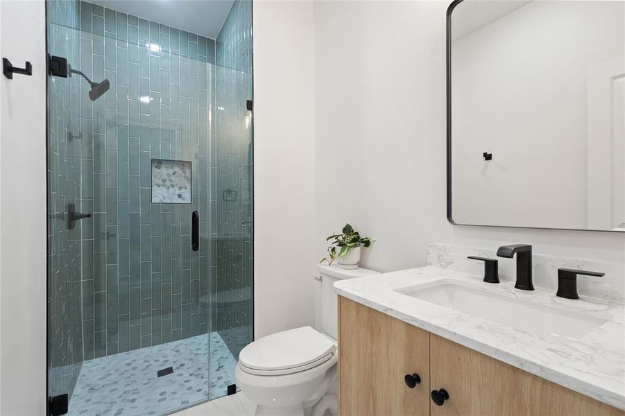 Bathroom featuring vanity, toilet, and a shower with shower door