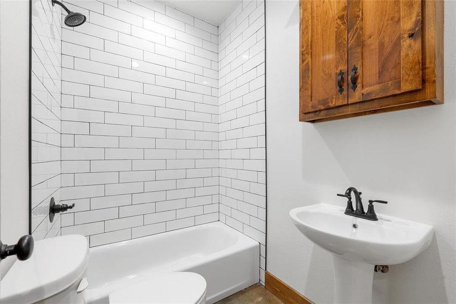 Full bath featuring toilet, baseboards, and bathtub / shower combination Full bath featuring toilet, baseboards, and bathtub / shower combination