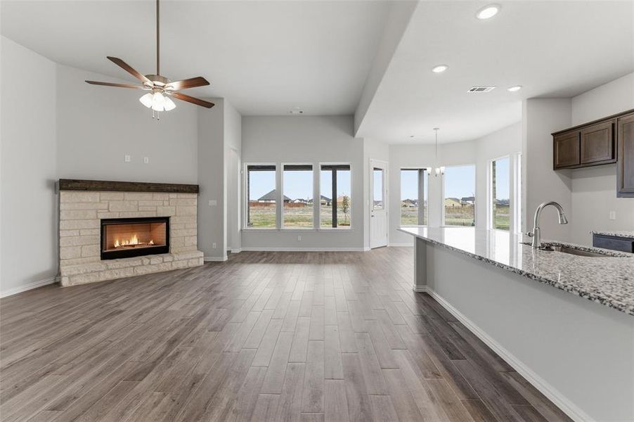 Unfurnished living room featuring dark wood finished floors, a fireplace, ceiling fan, and a chandelier