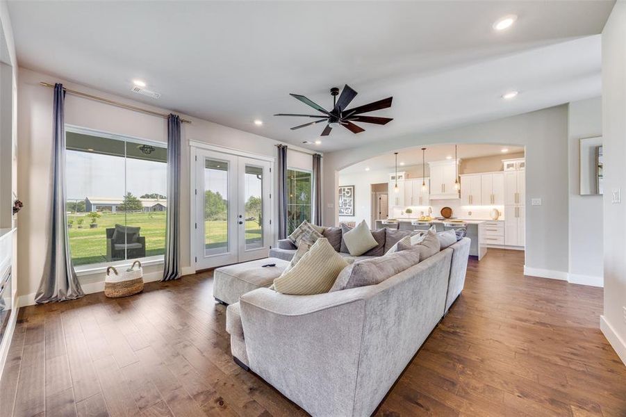 Living area featuring arched walkways, french doors, dark wood-type flooring, recessed lighting, and a ceiling fan