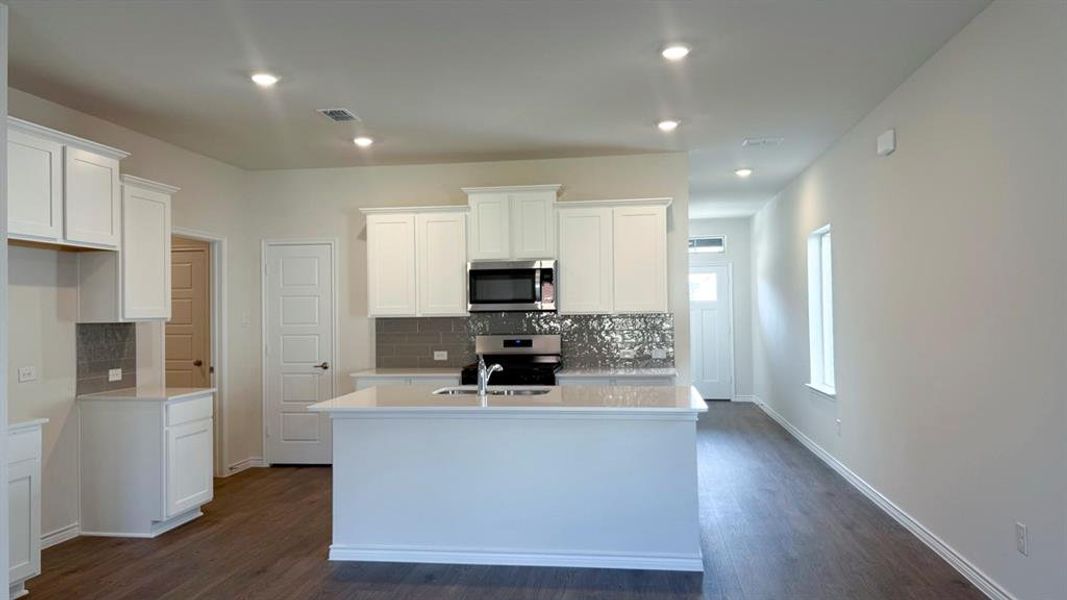 Kitchen featuring white cabinetry, tasteful backsplash, a center island with sink, appliances with stainless steel finishes, and recessed lighting Kitchen featuring white cabinetry, tasteful backsplash, a center island with sink, appliances with stainless steel finishes, and recessed lighting