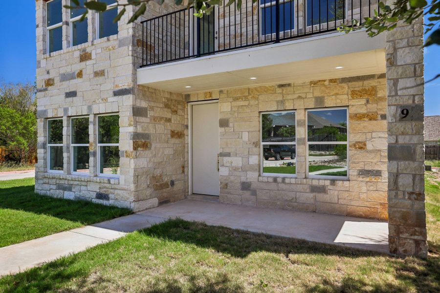 A stone facade and concrete walkway lead to the modern front entry.