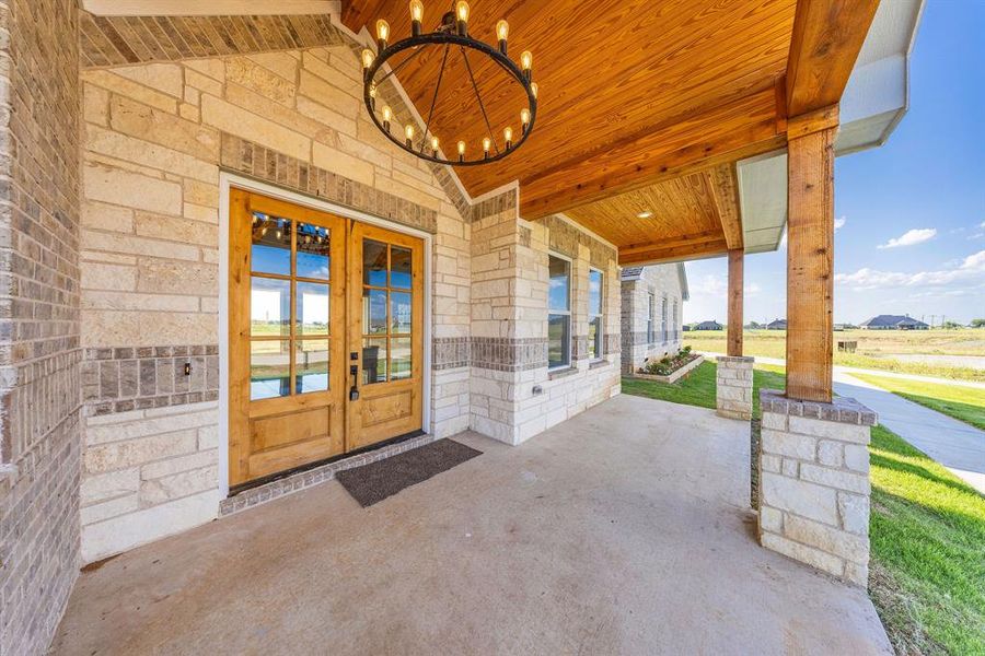 Property entrance with stone siding, french doors, and a porch Property entrance with stone siding, french doors, and a porch