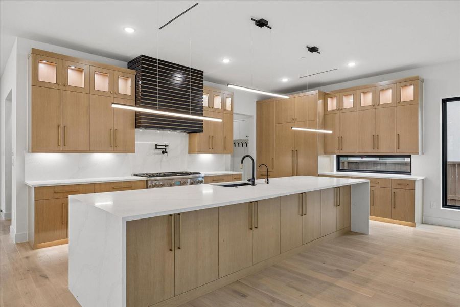The Refrigerator hides from view on the far wall next to the Butler Pantry as its wood cover surface blends with the rest of the custom cabinetry. Upper display shelves are internally lit. Bar seating at the island allows guests to visit with the Chef at meal preparation time. Great extra storage in the lower cupboards at the island across its length are visible here.