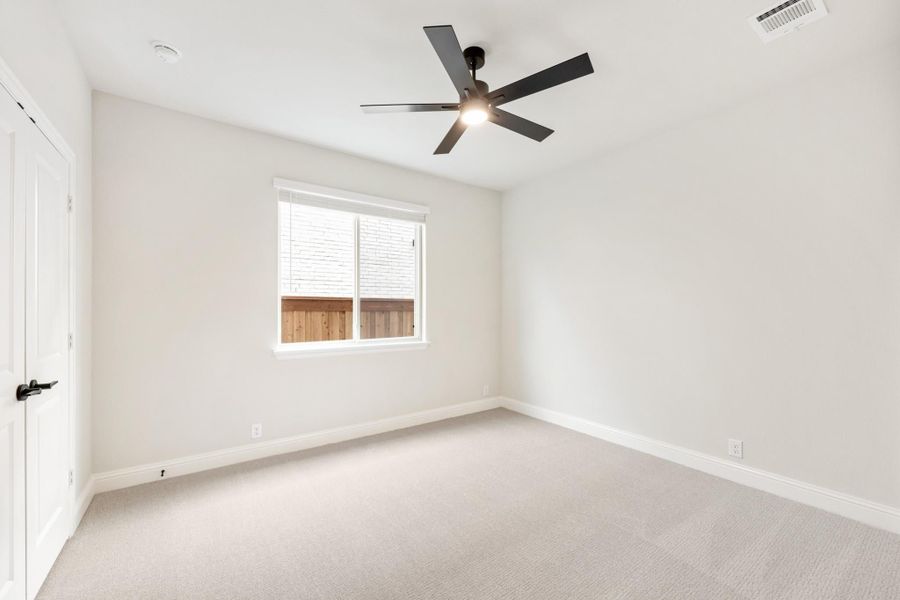 Empty bedroom with white walls, carpet flooring, black ceiling fan, and single window