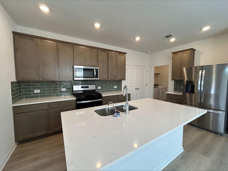 Kitchen featuring independent washer and dryer, stainless steel appliances, backsplash, light wood-style flooring, and recessed lighting Kitchen featuring independent washer and dryer, stainless steel appliances, backsplash, light wood-style flooring, and recessed lighting