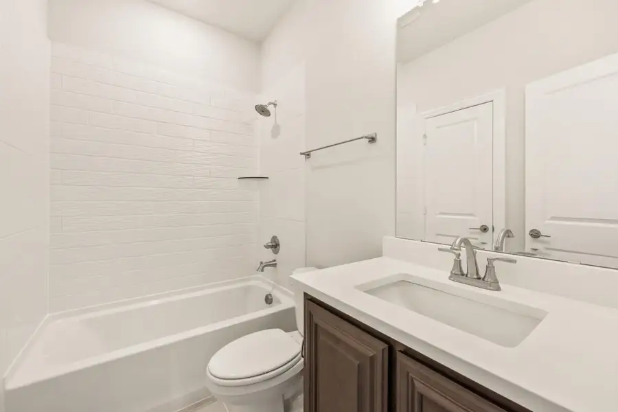 Bathroom with white subway tile tub surround, dark wood vanity, and white countertop