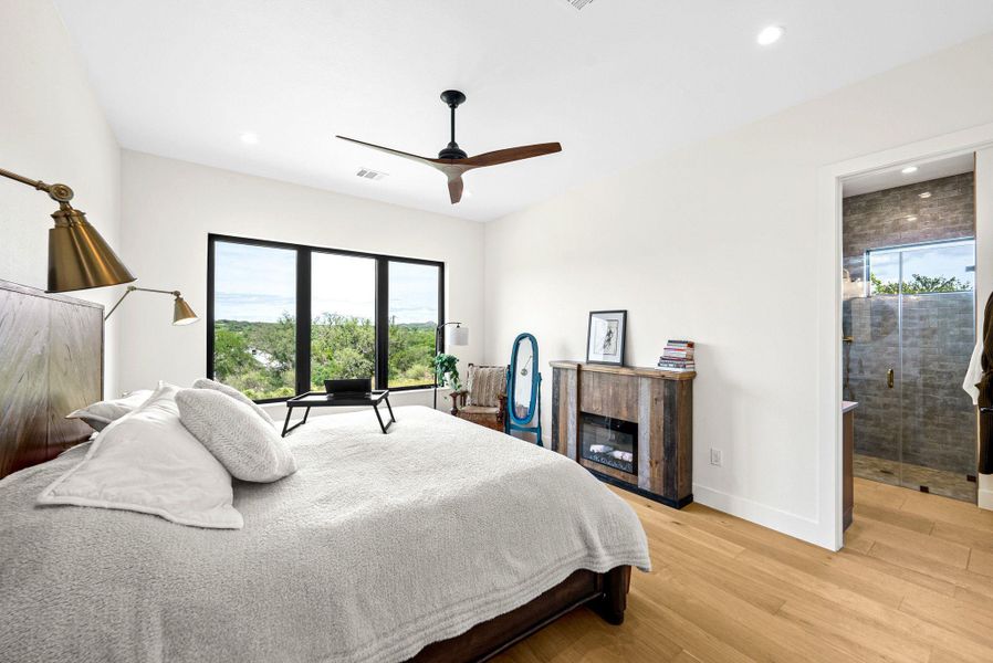 Hardwood floors and large windows frame peaceful outdoor views in this inviting bedroom suite.