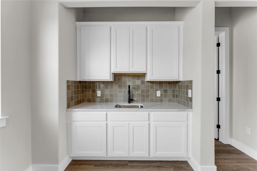 Kitchen with white cabinetry, backsplash, light stone countertops, and dark wood-style floors