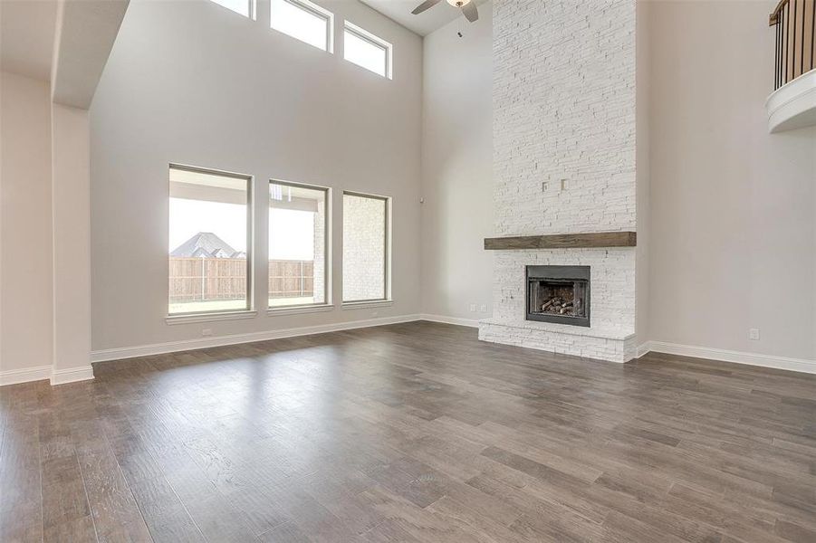 Unfurnished living room with a high ceiling, ceiling fan, a fireplace, and dark hardwood / wood-style flooring