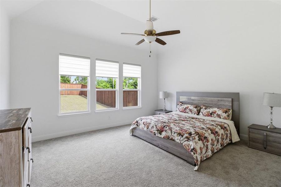 Room featuring three large windows with blinds, a vaulted ceiling, and a ceiling fan with integrated lighting