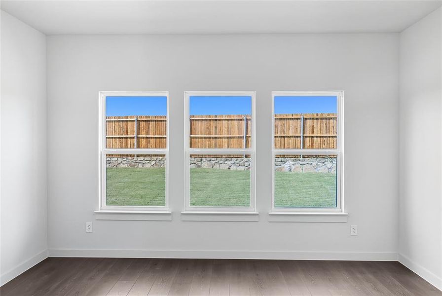 Spare room with plenty of natural light and wood finished floors Spare room with plenty of natural light and wood finished floors