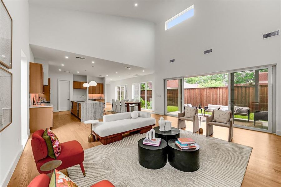 Expansive open-concept living space featuring high ceilings, wood-finish flooring, and recessed lighting