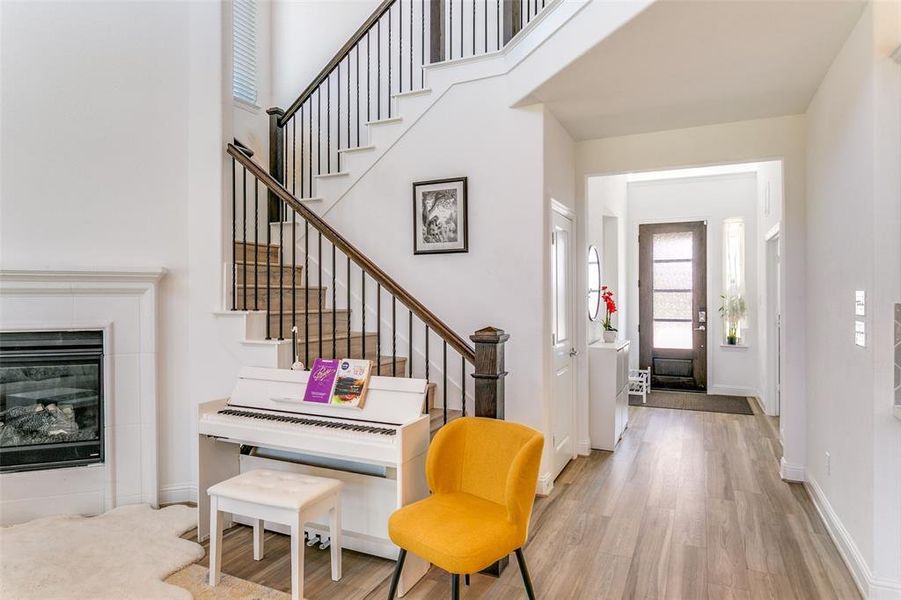 Entryway featuring a tiled fireplace, wood finished floors, stairway, and a towering ceiling