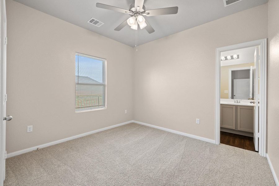 Unfurnished bedroom with light colored carpet, a ceiling fan, and ensuite bathroom