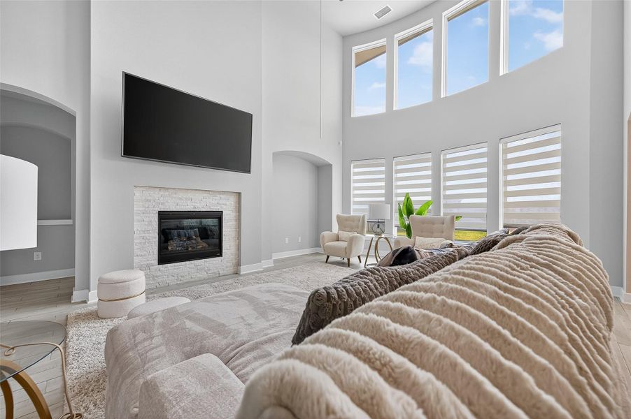 Expansive windows and custom shades elevate the comfort and style of this stunning living space. The modern fireplace adds warmth and visual interest beneath soaring ceilings.