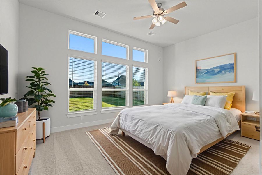 Virtually staged — The spacious primary suite comes to life with this warm and inviting layout, showing how easily you can create a relaxing retreat. Large windows fill the room with natural light, offering beautiful backyard views and plenty of space for a cozy seating area. *Photo Staged*