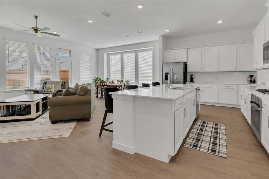 Kitchen featuring backsplash, white cabinetry, a breakfast bar, light wood-type flooring, and recessed lighting