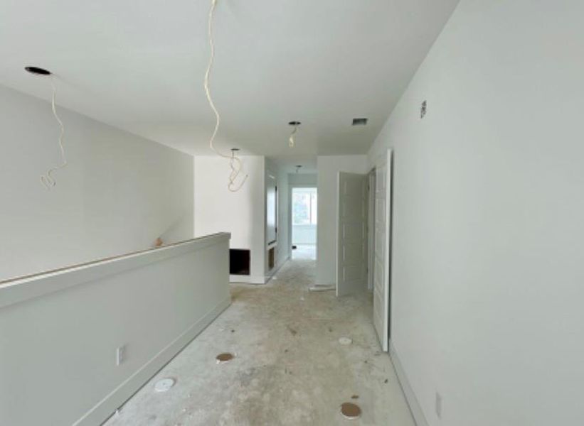 Corridor with an upstairs landing and unfinished concrete flooring Corridor with an upstairs landing and unfinished concrete flooring