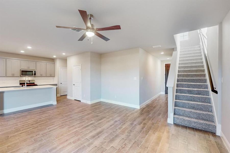 Unfurnished living room with light hardwood / wood-style flooring, ceiling fan, and sink